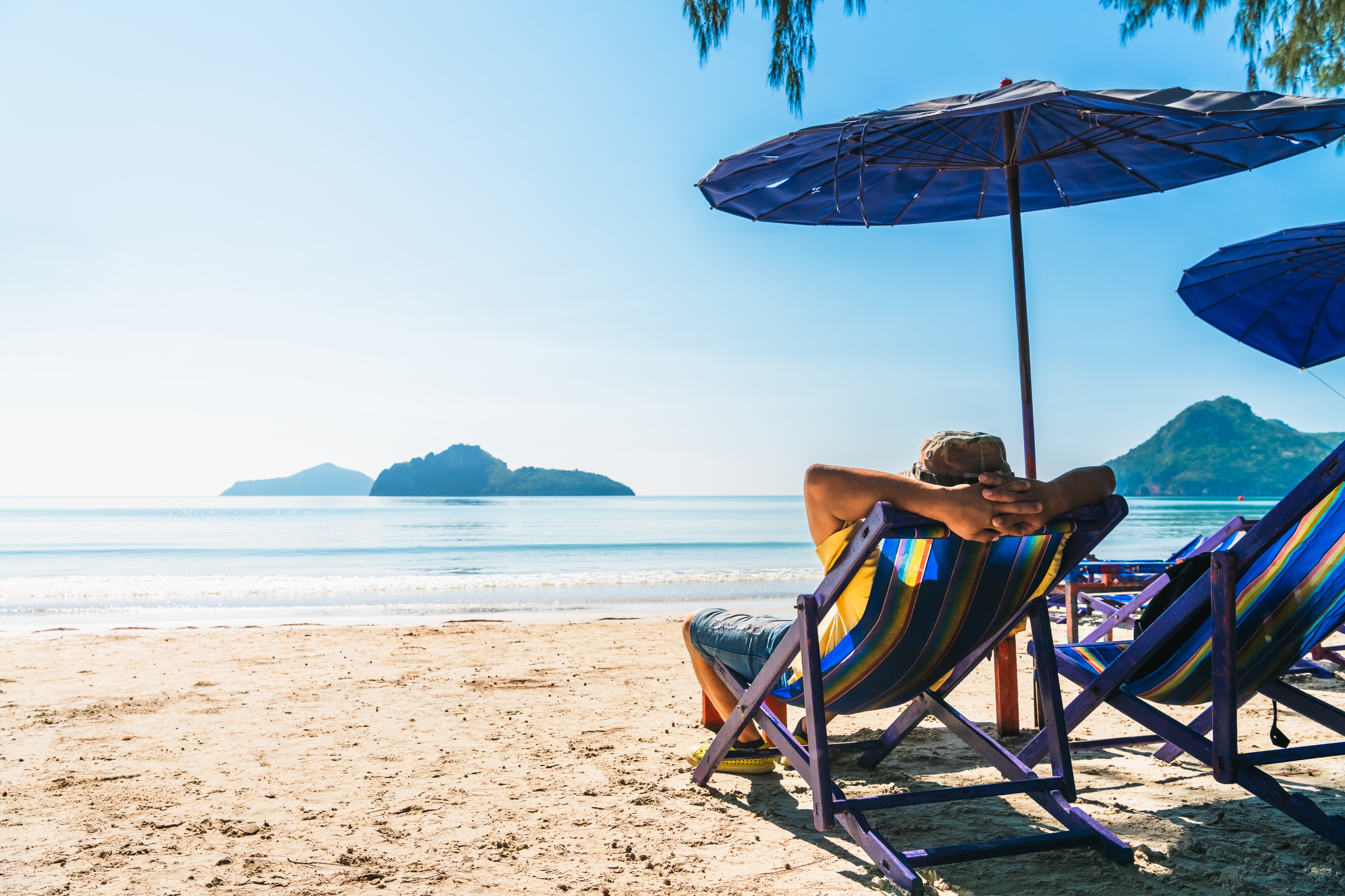 Person im Liegestuhl am Strand: Mit einfachen Tipps lässt sich Reisedurchfall vorbeugen.